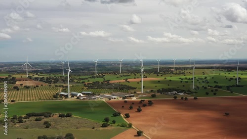 Aerial views showcase stunning wind turbines standing tall amidst vibrant fields and rich brown soil. Nature and technology blend harmoniously under a clear sky.