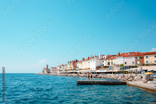 Coastal promenade and colorful seaside buildings in Piran, Slovenia along the Adriatic Sea on a sunny summer day