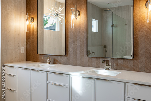 Modern luxury bathroom vanity with double undercounter sinks chrome faucets large mirrors and elegant wall sconce lighting