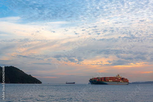 Cargo ship arriving at the Port of Santos at sunset.