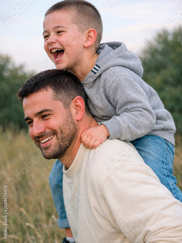 Happy Father Giving Son Piggyback Ride Outdoors