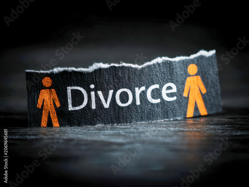 Torn paper with symbolic orange male and female figures representing separation and divorce concept on dark surface background