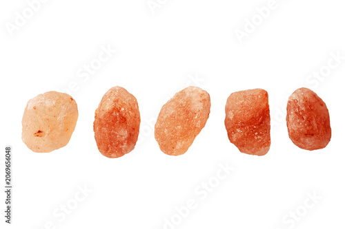 Five natural pieces of raw Himalayan pink salt rocks arranged in row. Organic mineral crystals used for cooking and wellness, isolated on white background.