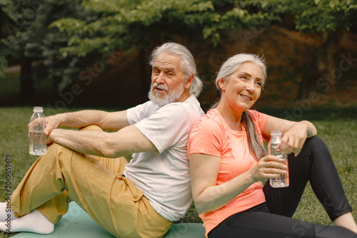 Senior couple sitting on exercise mats at park and resting