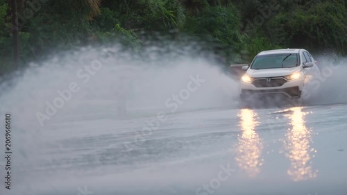 Hurricane rainfall flooded Florida road with evacuating cars and surrounded with water houses in suburban residential area.