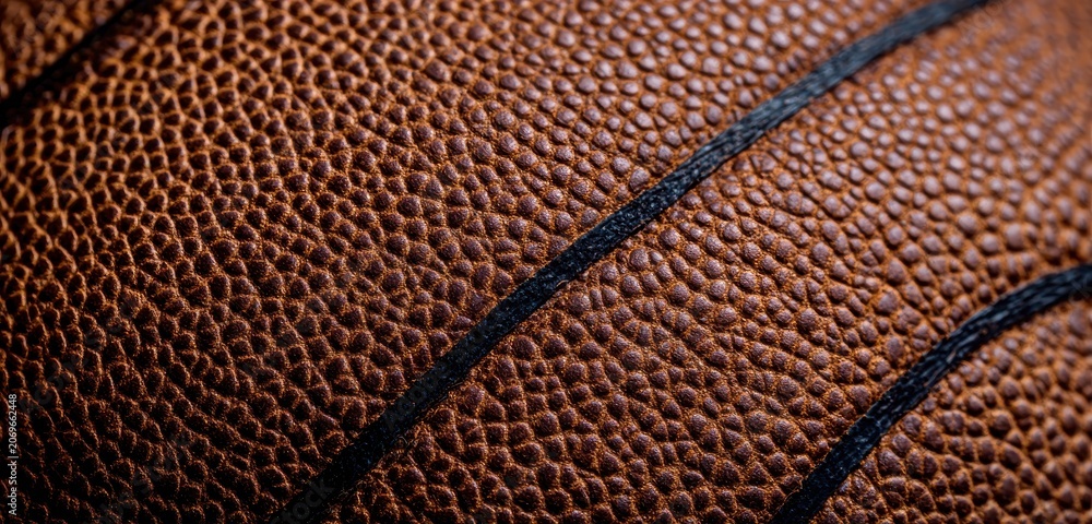 Fototapeta premium Detailed macro shot of textured basketball leather and black seam line with basketball background equipment close-up material professional physical competition training exercise abstract