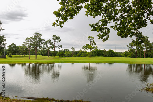 Tranquil Golf Course Landscape with Trees Reflected in Calm Pond under Overcast Sky at Tyler, Texas
