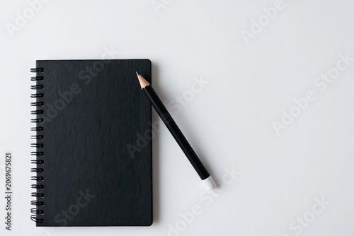 Notebook and black spiral journal with pencil on a minimalist white office desk