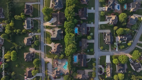 Aerial perspective of suburban neighborhood in Johnson City Tennessee featuring various residential homes lush green lawns swimming pools with tree-lined streets organized layouts evident in scene