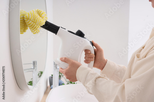 Woman steam cleaning mirror...