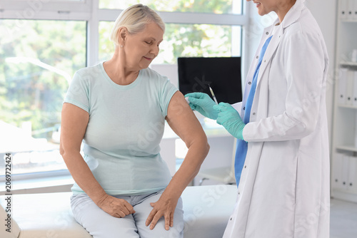 Female doctor vaccinating senior woman in clinic