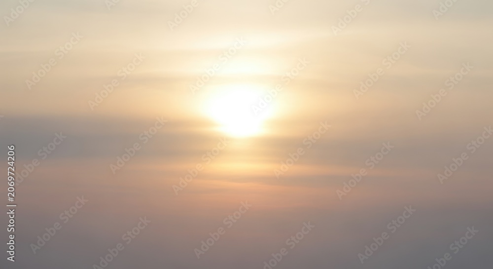 Fototapeta premium Bright golden sun shining through soft morning clouds at sunrise.