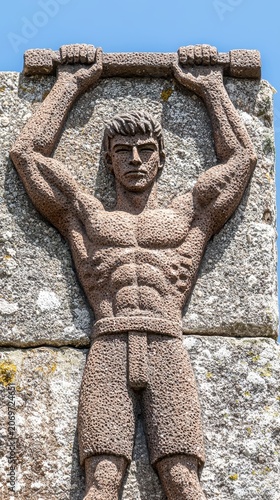 Weathered Stone Relief Sculpture of Muscular Man Lifting Heavy Object