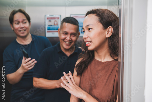 Foto A young asian woman cringes while rebuking advances from two creepy men trying to get her name while inside an elevator