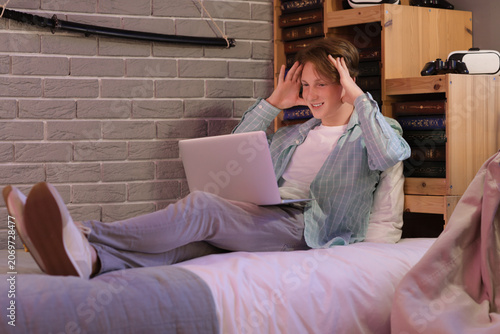 Male student using laptop in bedroom at night