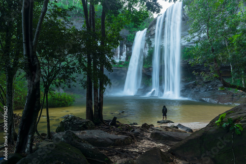 Young man relaxing at the waterfall in deep forest, Travel Concept.