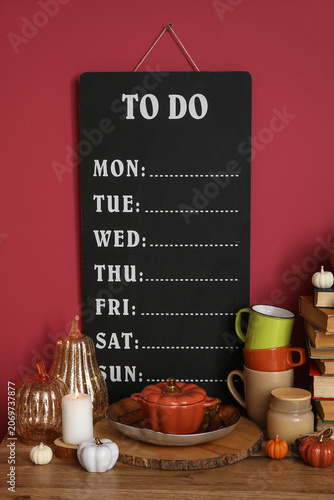 Obraz na plátně Dishes, autumn decor and blank to do list on wooden table near color wall