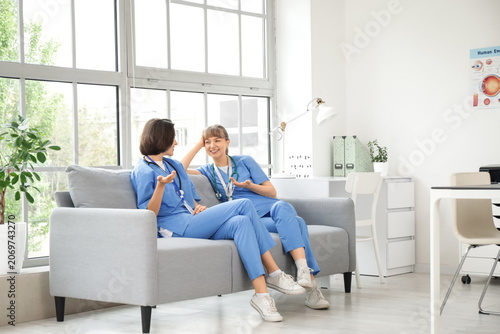 Female medical interns talking on sofa in clinic