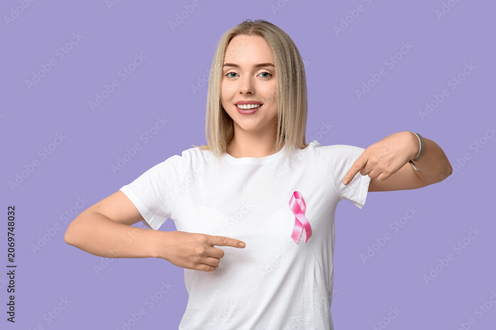 Fototapeta premium Young woman with pink ribbon on lilac background. Breast cancer awareness concept