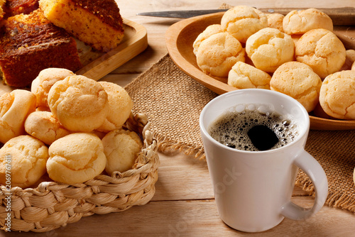 Brazilian breakfast with fresh black coffee and homemade cheese bread served in rustic baskets and platters, accompanied by corn cake.