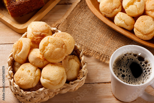 Fotografía A cup of black coffee accompanied by homemade cheese bread, served in a natural fiber basket on a rustic wooden table