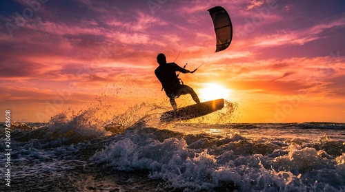 Kitesurfer jumping over ocean waves at vibrant sunset