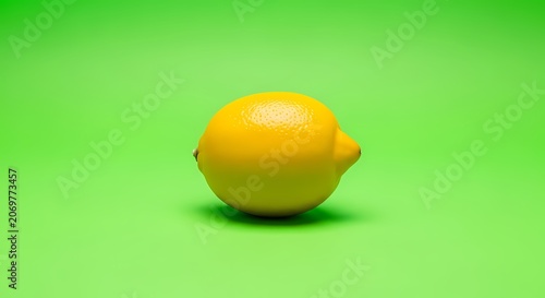 Single Yellow Lemon on Vibrant Green Background, Studio Shot, Fresh Fruit