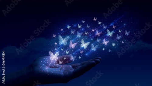 Glowing magical butterflies flying from open hand against dark blue sky
