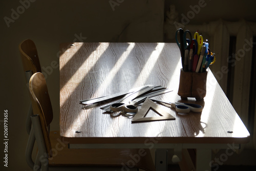 A sunlit school desk with various stationery and tools for learning.