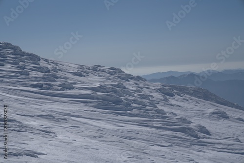 Wind sculpted snow slopes with mountains in winter, Japan