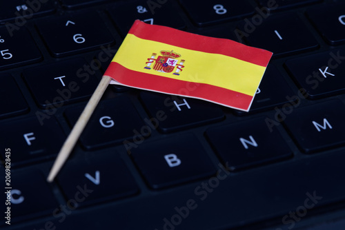 Spanish flag on computer keyboard symbolizing digital economy, IT regulations, online work and high-tech job market in Spain