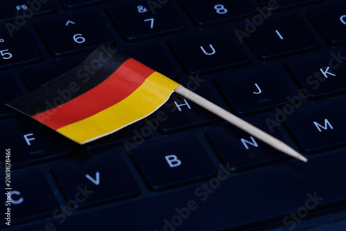 German flag on computer keyboard symbolizing digital economy, IT regulations, online work and high-tech job market in Germany.