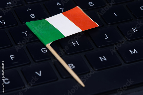 Italian flag on computer keyboard symbolizing digital economy, IT regulations, online work and high-tech job market in Italy.