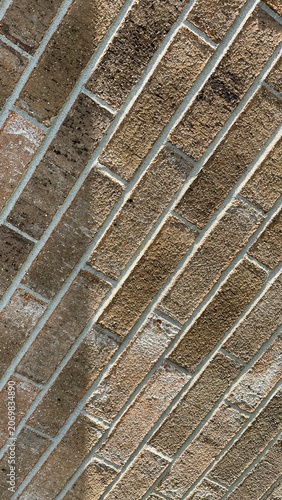 Abstract brown brick wall texture background with diagonal pattern. Close up perspective of modern brown brickwork facade masonry. Artistic shade line over a prespective brownish brick wall.