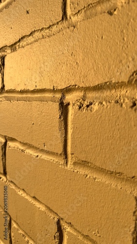Abstract yellow brick wall texture background with side perspective. Cool yellow brick wall background at golden hour. Close up perspective of painted yellow brick wall interior facade.