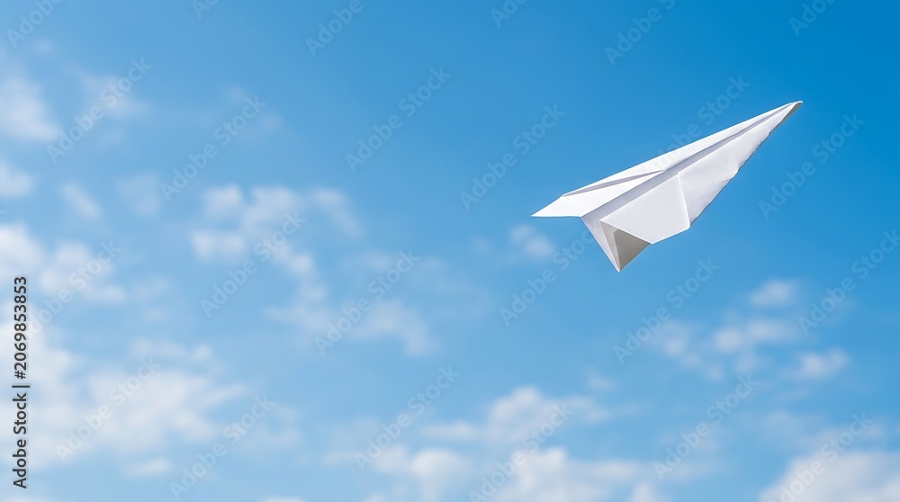 Fototapeta premium Paper airplane flying through a clear blue sky with soft clouds