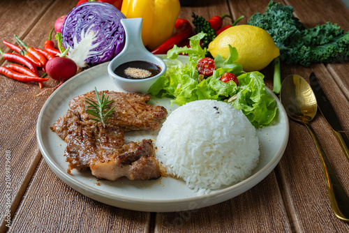 Healthy balanced meal concept. Roasted pork with rice, salad, and colorful raw ingredients like bell pepper, kale, and chili around the plate.