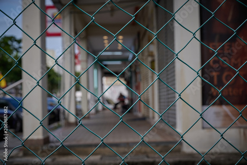 Chain Link Fence with Blurred Urban Walkway Background