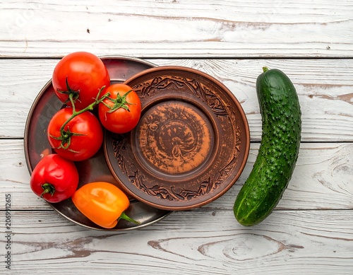 A still life of fresh produce displayed on a rustic wooden table with decorative plates. Brightly colored and inviting