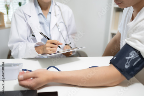 Obraz na plátně Doctor records patient's blood pressure reading