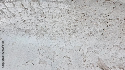  Gray painted concrete surface exposed to steady rainfall, creating a textured wet urban backdrop. Water droplets and reflective details highlight stormy weather and outdoor architecture