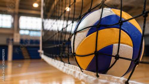 A colorful volleyball hitting the net in a bright indoor sports gymnasium court