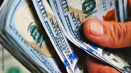 Close-up of hands counting a stack of 100 US dollar banknotes quickly. Concept of cash transaction, financial management, salary payment, accounting audit, business liquidity, and wealth.