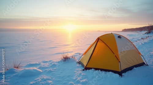 Yellow camping tent sitting on a snowy landscape during a beautiful winter sunset