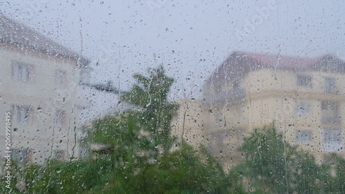 Heavy summer rain outside. Strong wind and rain drops falling on glass window