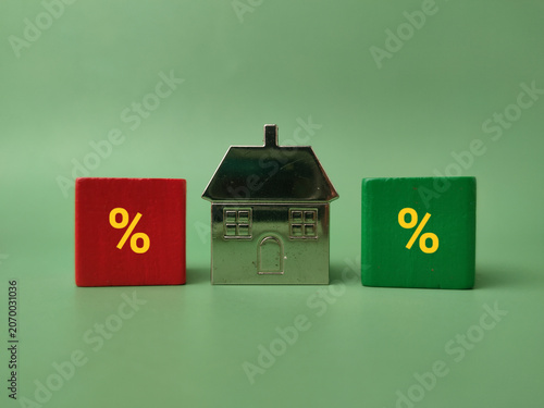 A silver model house sits positioned between a red block and a green block, both displaying yellow percentage symbols