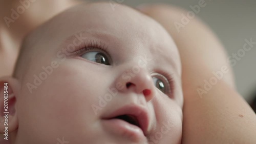 Teething baby lying down, chewing toy and moving hands and feet actively. Top view of sweet infant crying and smiling during first teeth growth milestone. Pediatric and parenting concept.