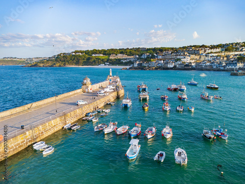 Aerial view of fishing boats moored in the turquoise waters of St Ives Harbour next to Smeaton's Pier and the coastal town in St Ives, England, United Kingdom.