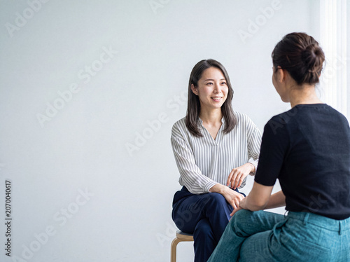 Foto Authentic photograph of two Asian women engaged in a friendly discussion or interview indoors