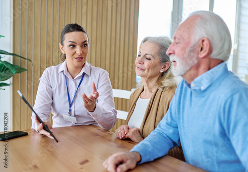 Senior couple having a meeting with an agent, businesswoman, salesperson or doctor using a tablet computer  in his office